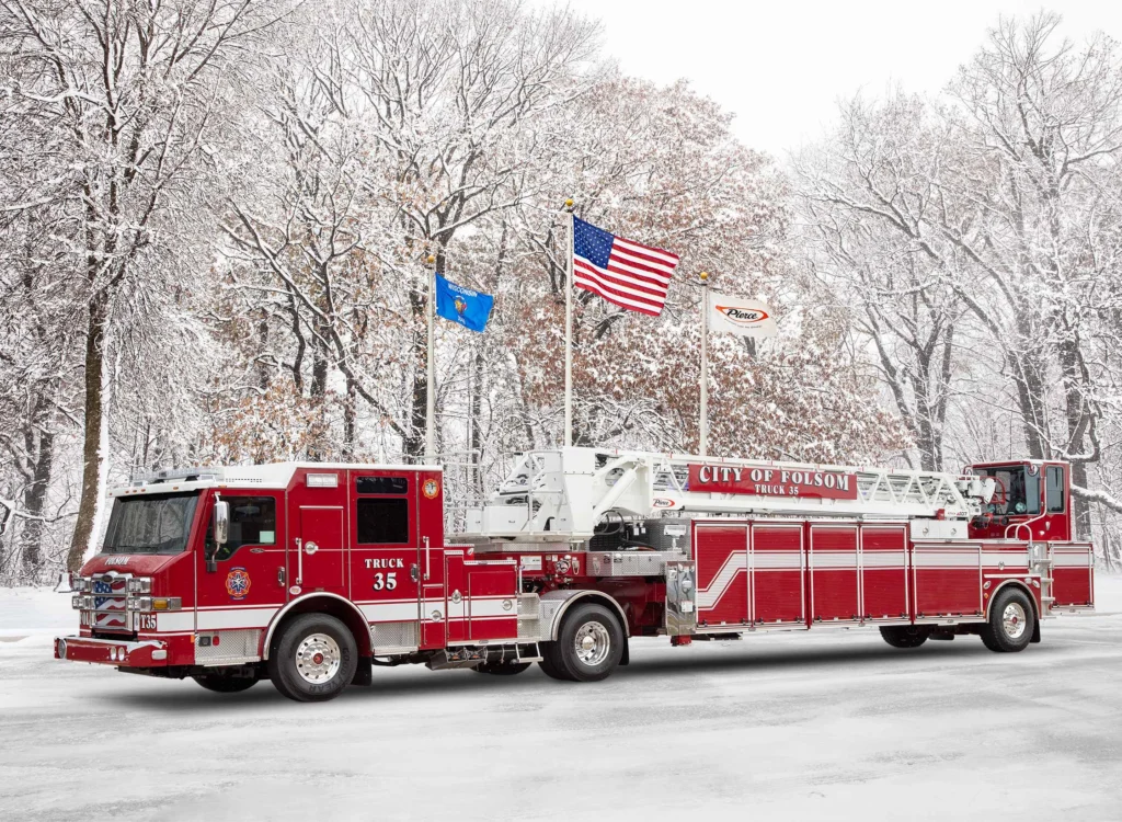 a fire truck in front of flag poles with snow on the ground
