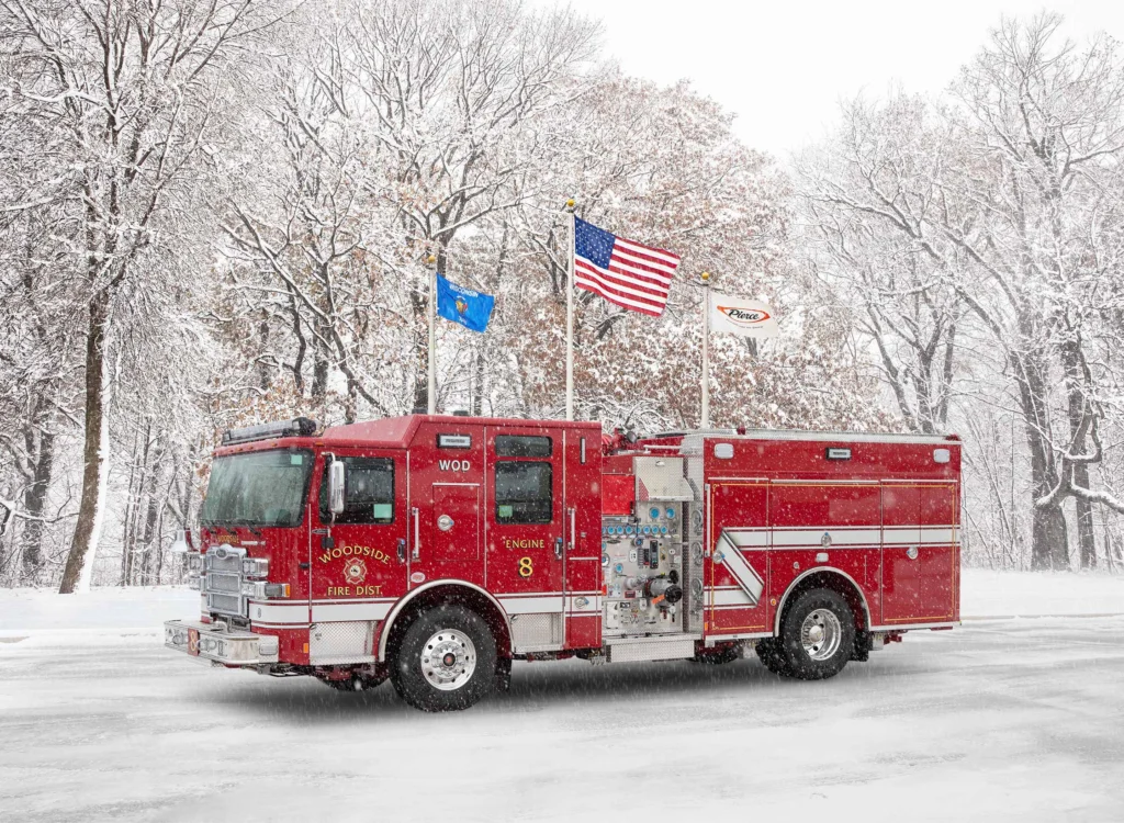 a fire truck in front of flag poles with snow on the ground
